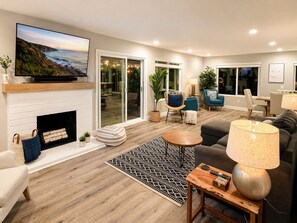 A modern living room with a fireplace, a television, and a large window overlooking a patio.