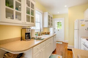 A kitchen with white cabinets, a coffee maker, a sink, and a refrigerator.