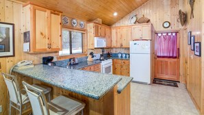 A kitchen with wooden cabinets, granite countertops, a refrigerator, a stove, and a sink. - (21) River Refuge at The Redwoods In Yosemite (Yosemite National Park)
