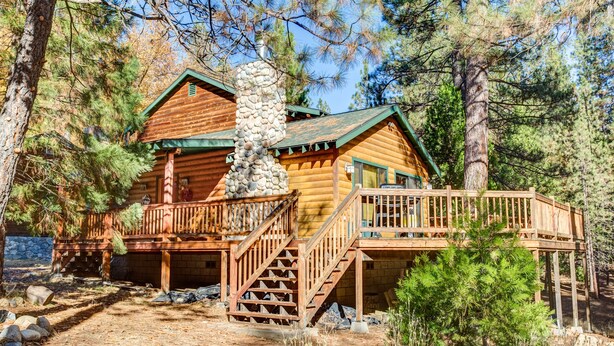 A log cabin with a wooden deck and stairs leading to a porch. - (21) River Refuge at The Redwoods In Yosemite (Yosemite National Park)