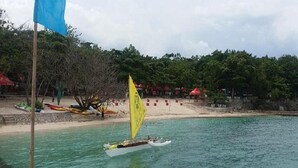 A small sailboat on calm water with a sandy beach and trees in the background. - Mactan Newtown by Javadrea (Lapu-Lapu)