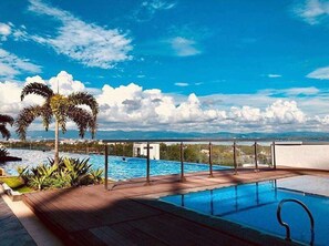 Ein Pool auf dem Dach mit freiem Blick auf das Meer und die dahinterliegenden Berge.