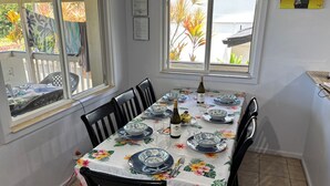 A dining area with a table set for four, featuring floral tablecloths and blue and white plates. - House of the Rising Sun (Laie)