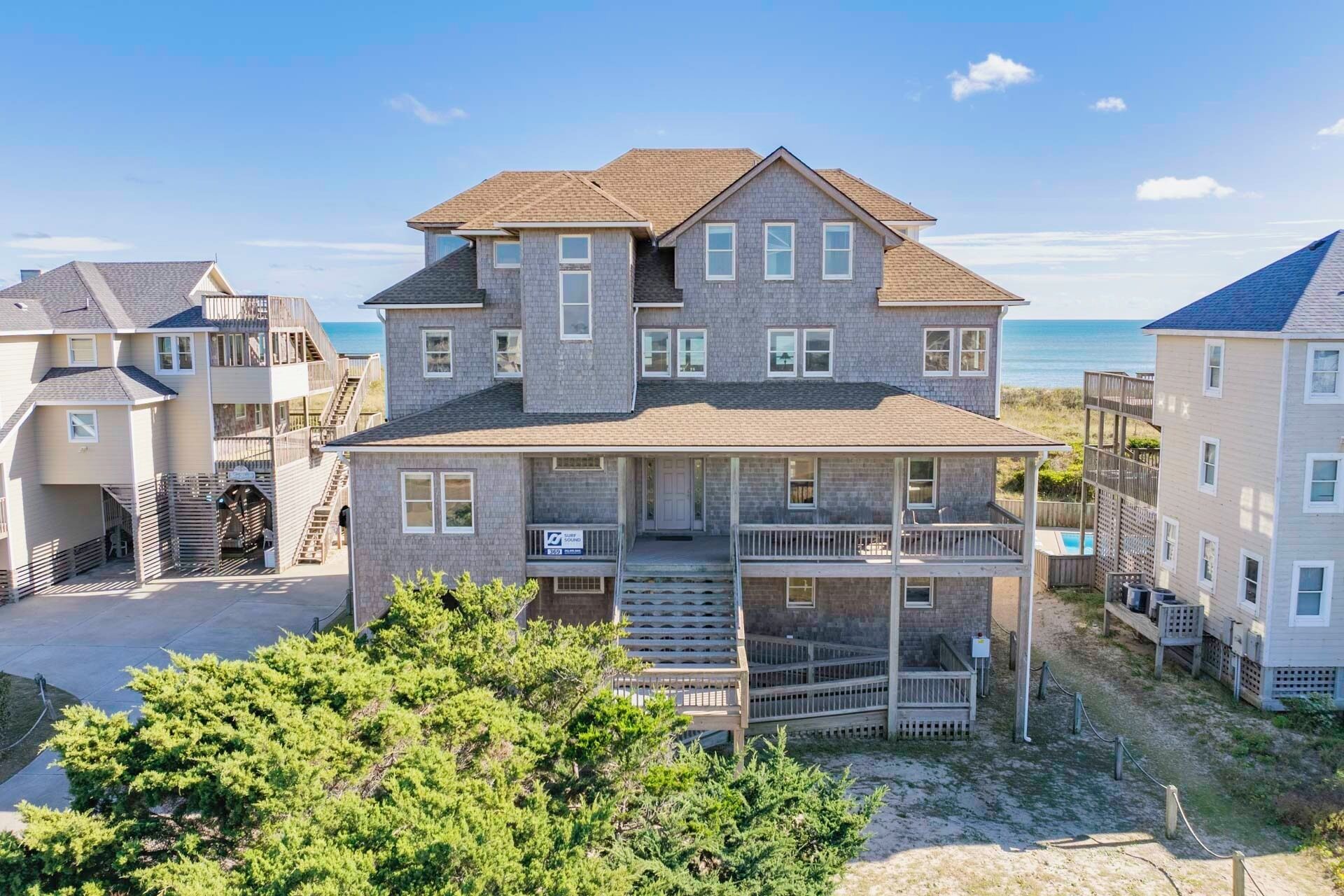 A two-story house with a balcony, a front porch, and a view of the ocean.