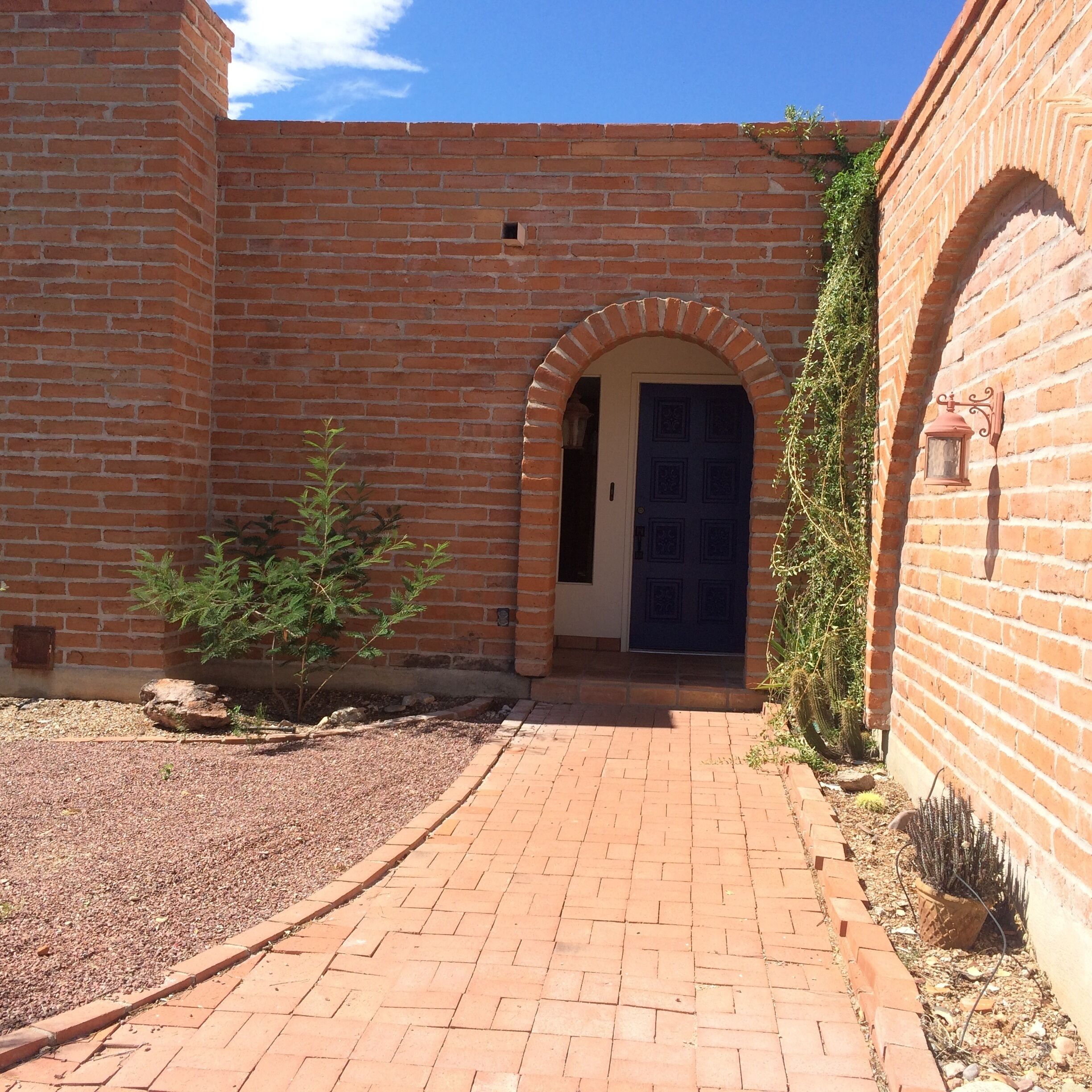 A brick building with a central archway leading to a door.