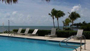 A pool area with lounge chairs and a view of the ocean. - Coral Cove Resort - ‘A Fisherman’s Dream’ (Islamorada)
