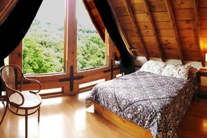 Een slaapkamer met een groot raam, een bed en een stoel.