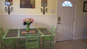 A dining area with a green table and chairs, a vase with flowers, and a door with a window. - Comfy & Cozy Right Downtown Charleston  OP2019-00450 (Charleston)