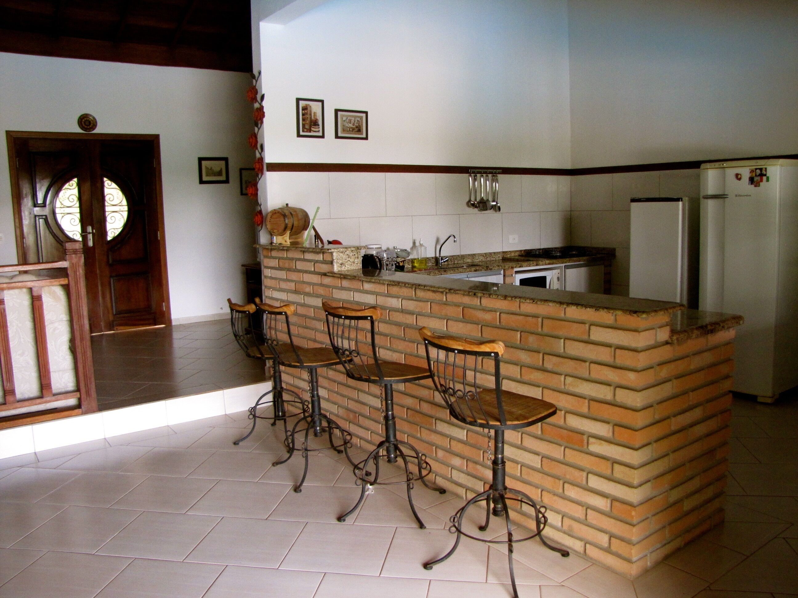 Una cucina con isola in mattoni, quattro sgabelli da bar, un frigorifero e un lavello.