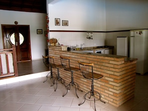 Una cucina con isola in mattoni, quattro sgabelli da bar, un frigorifero e un lavello.