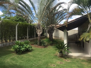 Un giardino curato con palme, un prato e un edificio con tetto in tegole.