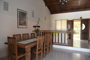 Un'area pranzo con un tavolo e sedie in legno, un vaso con fiori e un quadro appeso al muro.