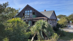 A two-story house with a steeply pitched roof, large windows, and a balcony.