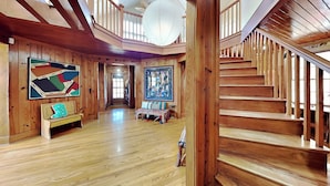 A spacious wooden interior with a staircase, wooden floors, and two benches.