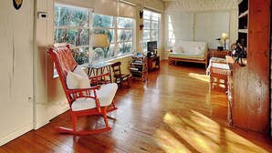 A spacious living room with a wooden floor, a rocking chair, a sofa, and a television.