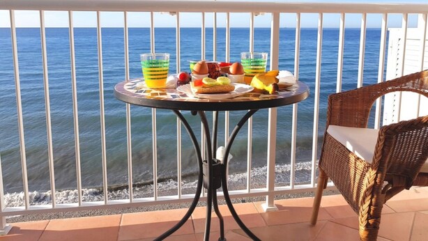 A balcony with a table set with breakfast items, overlooking the sea. - Frontline Apartment Great Views (Nerja)