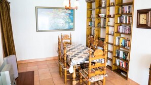 A dining area with a wooden table and chairs, a bookshelf filled with books, and a painting on the wall. - Frontline Apartment Great Views (Nerja)