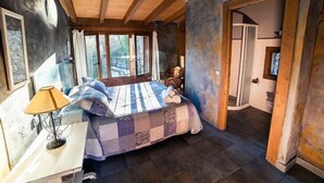 A bedroom with a large bed, a bedside table with a lamp, and a view of the outdoors through a window. - Rural house El Huerto de la Fragua for 5 people (Enciso)