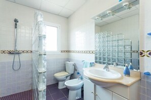 Un baño con ducha, inodoro, bidé y lavabo.