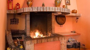 A brick fireplace with a fire, surrounded by shelves with decorative items.
