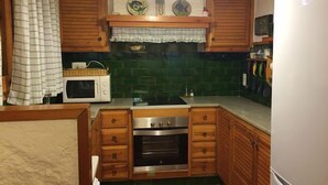 A compact kitchen with wooden cabinets, a microwave, an oven, and a refrigerator. - Self catering La Roureda for 9 people (Àger)