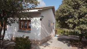 A white building with a tiled roof, a wooden window frame, and a stone base. - Self catering La Roureda for 9 people (Àger)