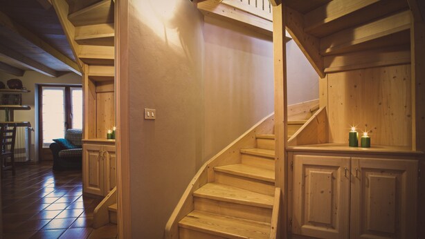 Una scala in legno con corrimano che porta a un pianerottolo con armadi.
