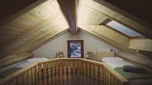 Una camera in stile dormitorio con due letti, una ringhiera di legno e lucernari.