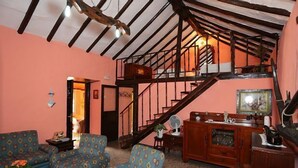 Una sala de estar acogedora con sofás estampados, una escalera de madera y un comedor con mesa y sillas.