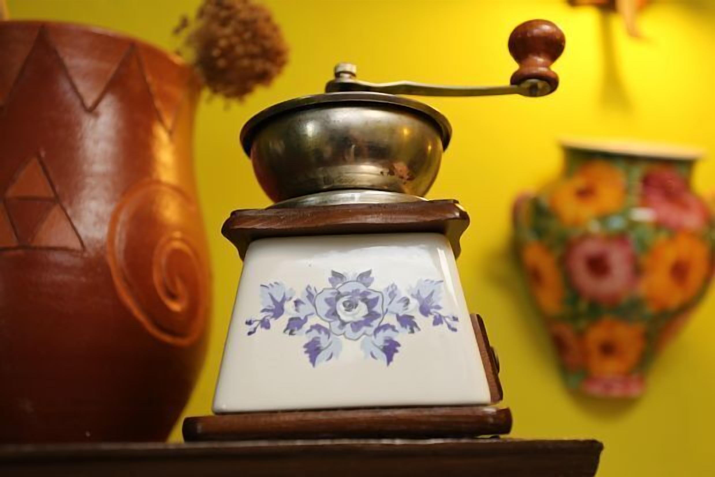 Een koffiemolen met een bloemendecor op de basis, geplaatst op een houten oppervlak.