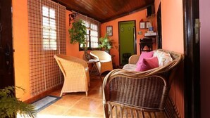 Una habitación acogedora con muebles de mimbre, una puerta verde y suelo de baldosas.