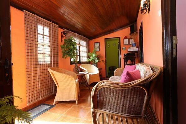 A cozy room with wicker furniture, a green door, and a tiled floor.