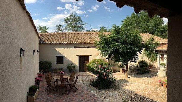 Une cour avec un patio carrelé, une table entourée de chaises et des plantes en pot.