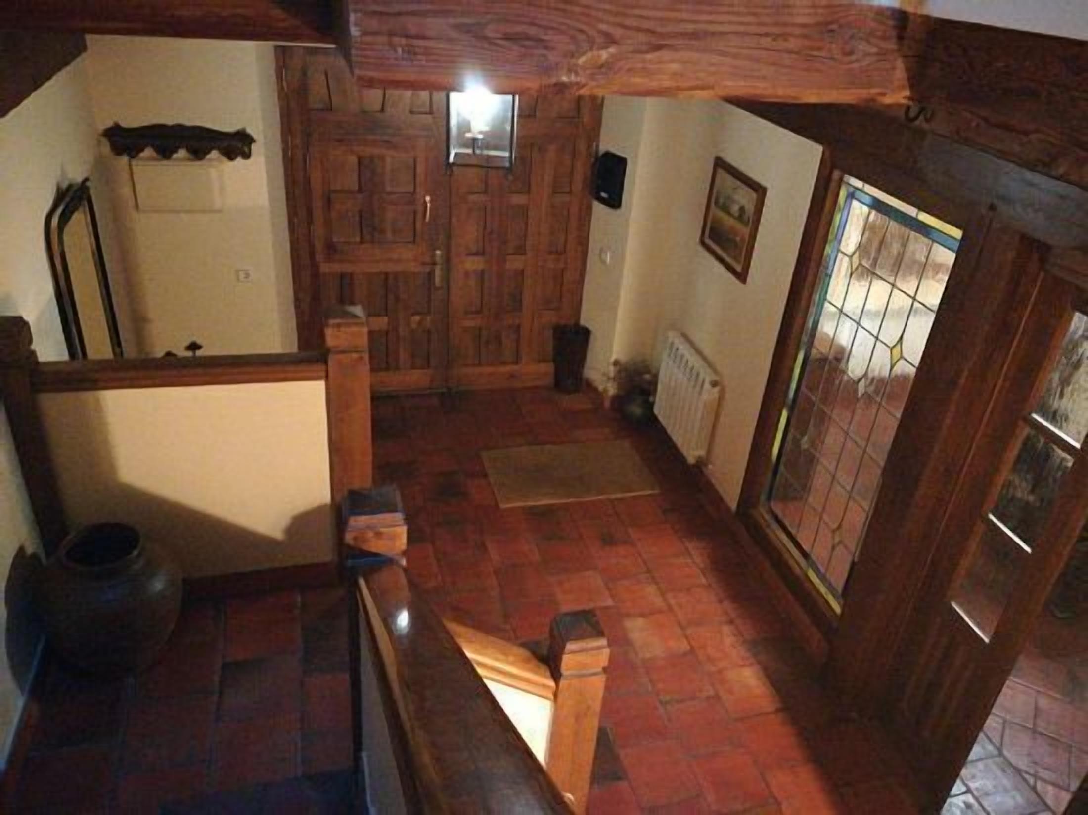 Interior de madeira com piso ladrilhado, porta de madeira e radiador.