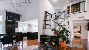 Un salon moderne avec un escalier, un coin repas et une cuisine.