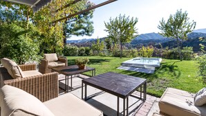 Une terrasse extérieure avec des meubles en osier, une piscine et une vue sur les montagnes.