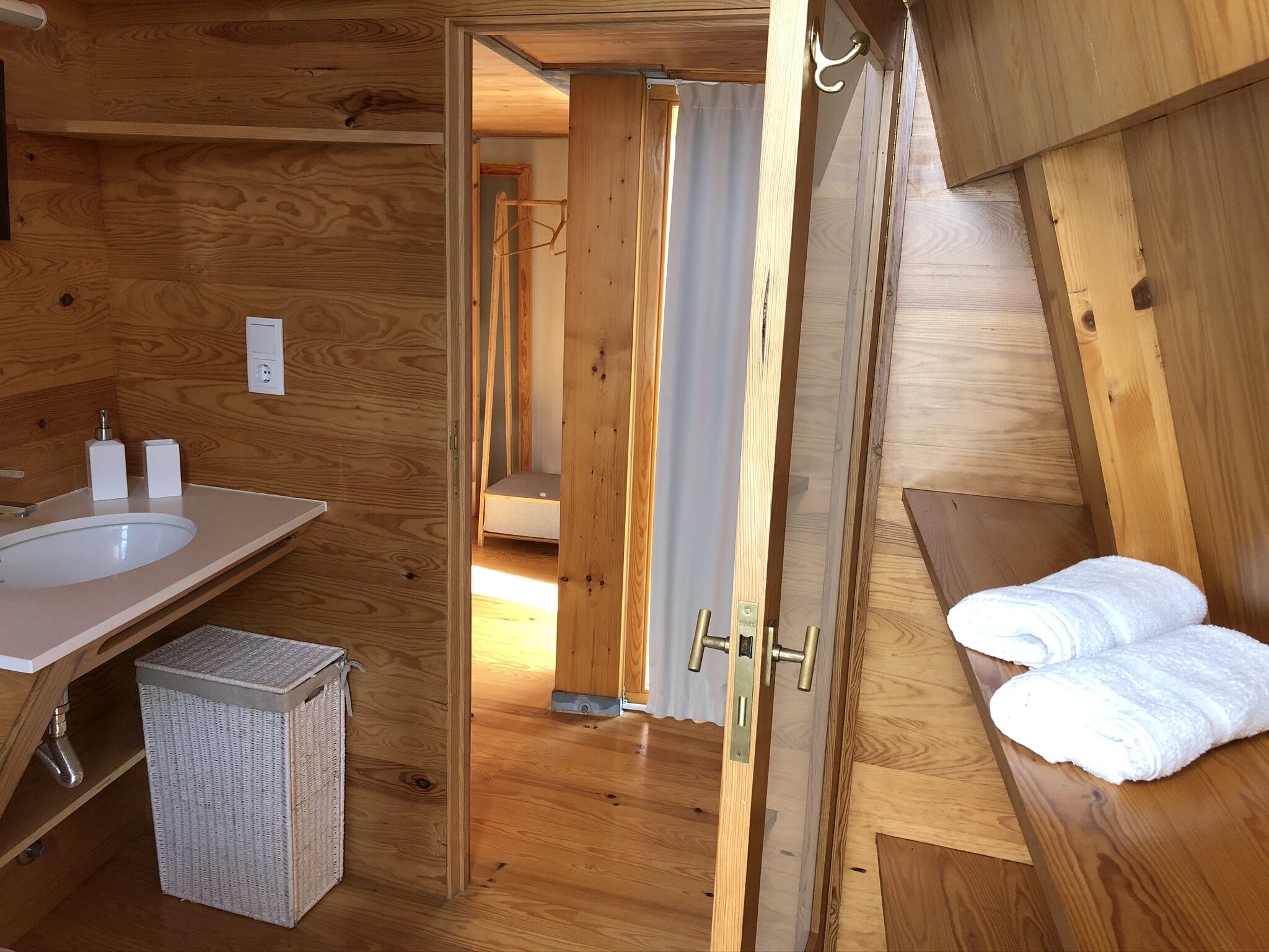 Een houten badkamer met een wastafel, spiegel en handdoekrek.
