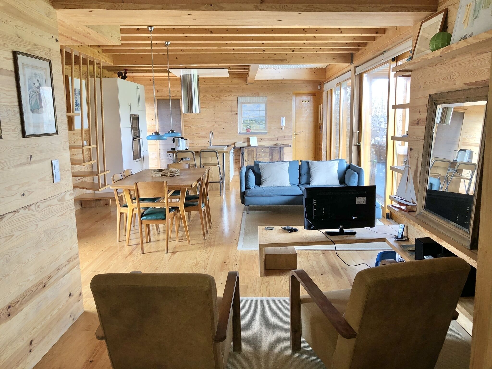 A spacious wooden interior with a dining area, a sofa, and a TV.