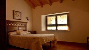 A bedroom with a wooden bed, a nightstand, a window with curtains, and a framed picture on the wall.
