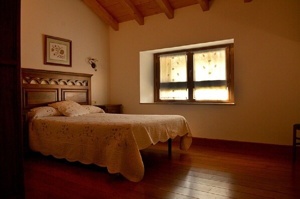 A bedroom with a wooden bed, a nightstand, a window with curtains, and a framed picture on the wall. - Casa Lenco for 8 people (Zilbeti)