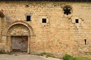 A stone building with an arched entrance, a circular window, and small rectangular windows. - Casa Lenco for 8 people (Zilbeti)