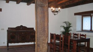 A dining area with a wooden table and chairs, a dark wooden cabinet, and a chandelier.