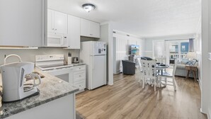 Een moderne keuken met witte kastjes, een ingebouwde magnetron en een koffiezetapparaat op het aanrecht.