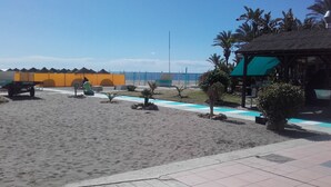 En badestrand med en sandsti, en lille pool og en pavillon.