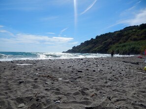 Une plage au paysage rocheux, où les vagues viennent se briser sur le rivage.