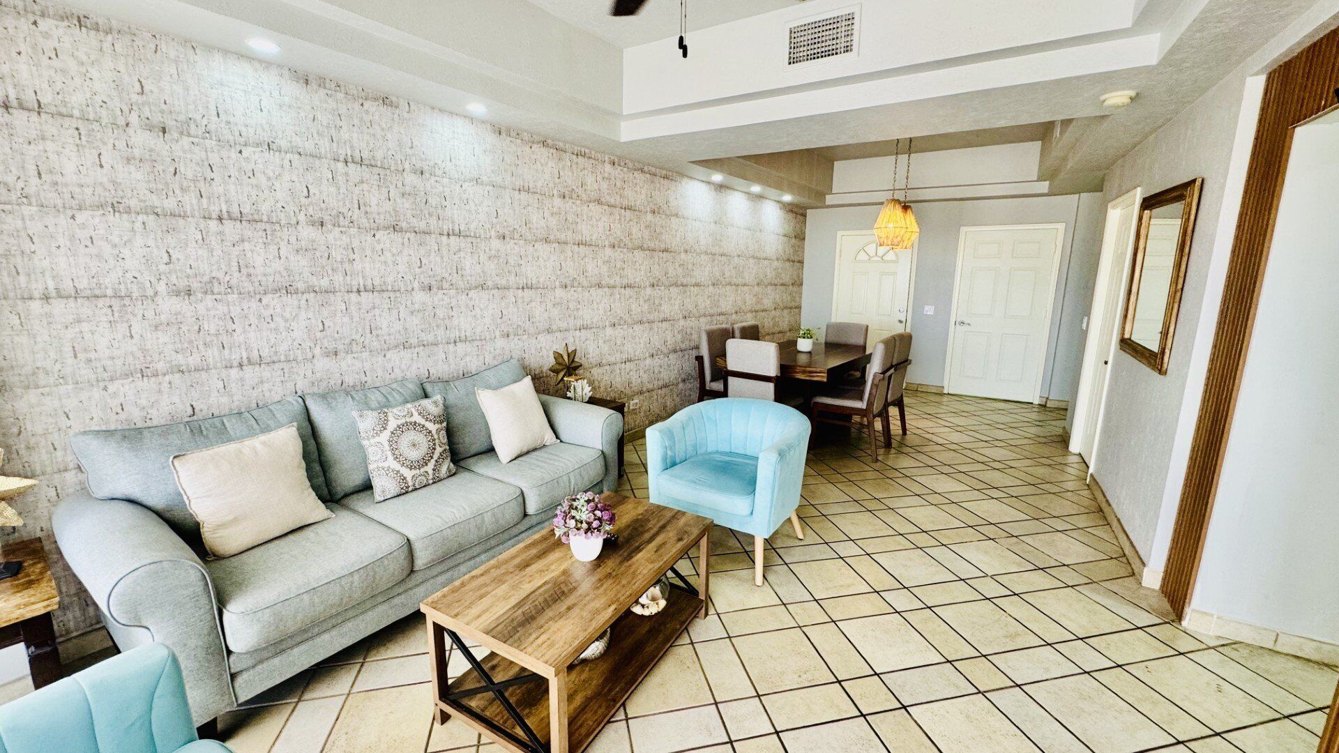 Uma sala de estar com sofá, mesa de centro e um espaço de jantar com cadeiras e mesa.