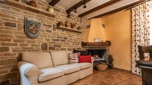 A stone-walled room with a beige sofa, a fireplace, and a shield emblem on the wall.