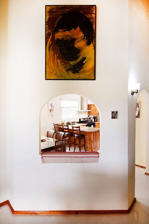 Uma sala de jantar com uma mesa grande, cadeiras e uma cozinha visível por um arco.