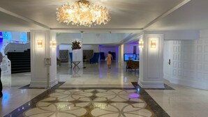 Eine geräumige Lobby mit einer Chandelier, einem gemusterten Boden und einer Sitzecke.