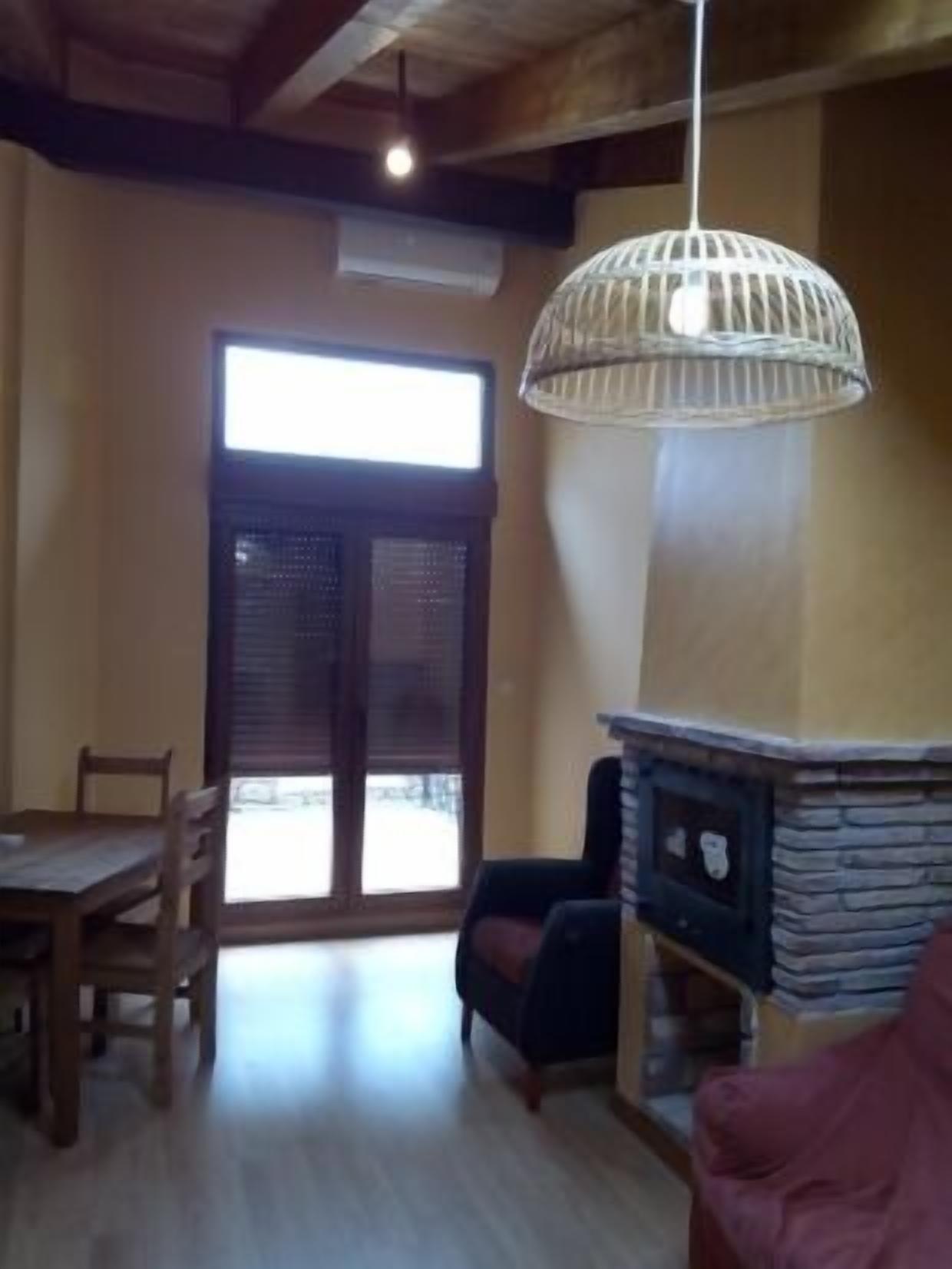 A dining area with a table and chairs, a fireplace, and a large window with blinds.